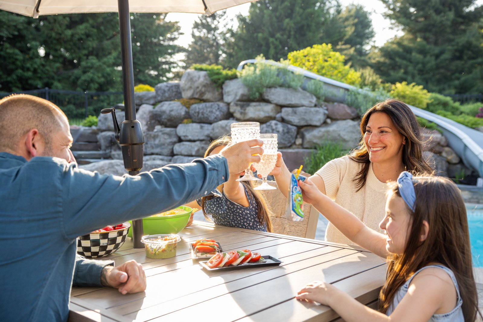 happy family seating food drinks table pool outside