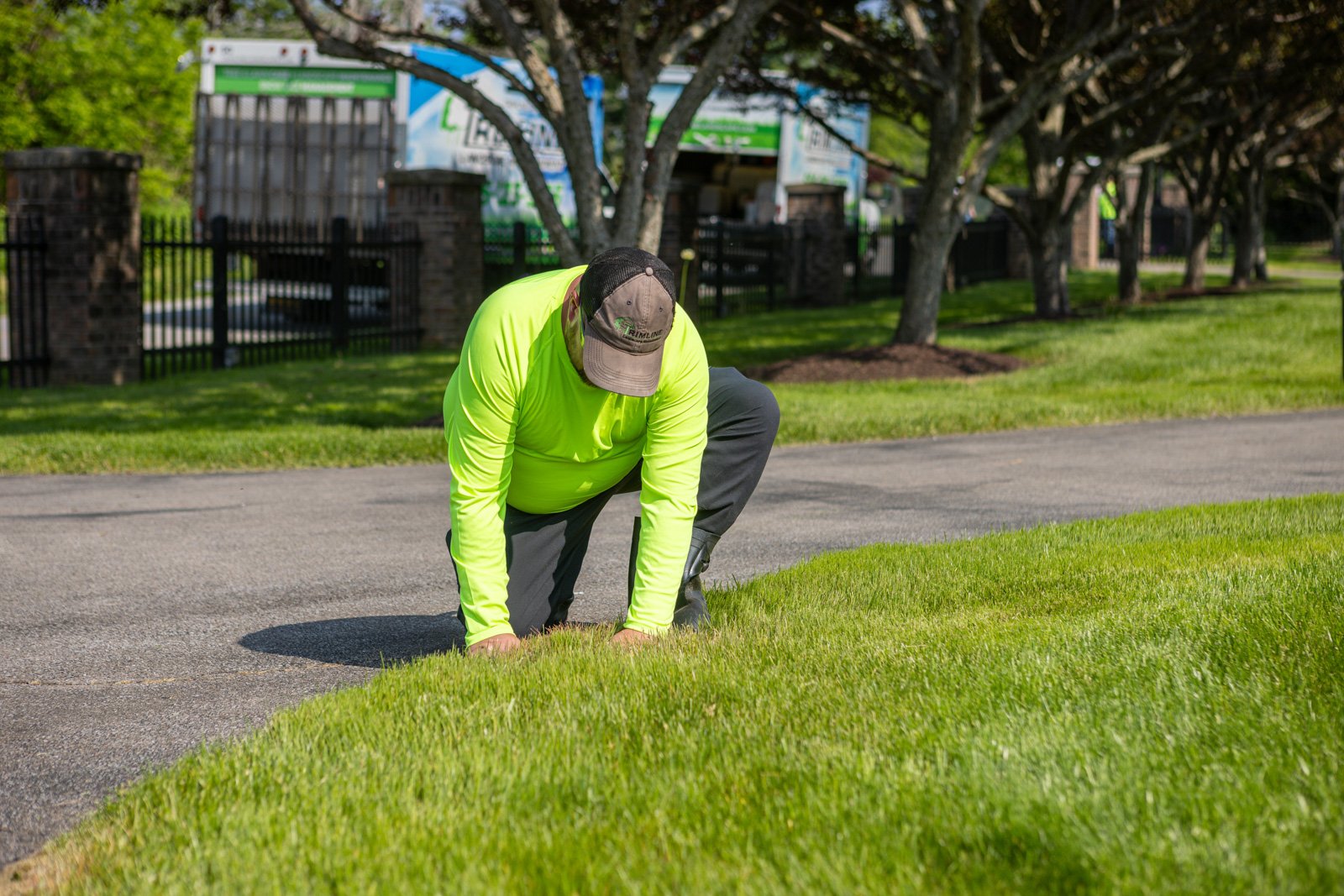 lawn care tech inspecting grass driveway truck in background